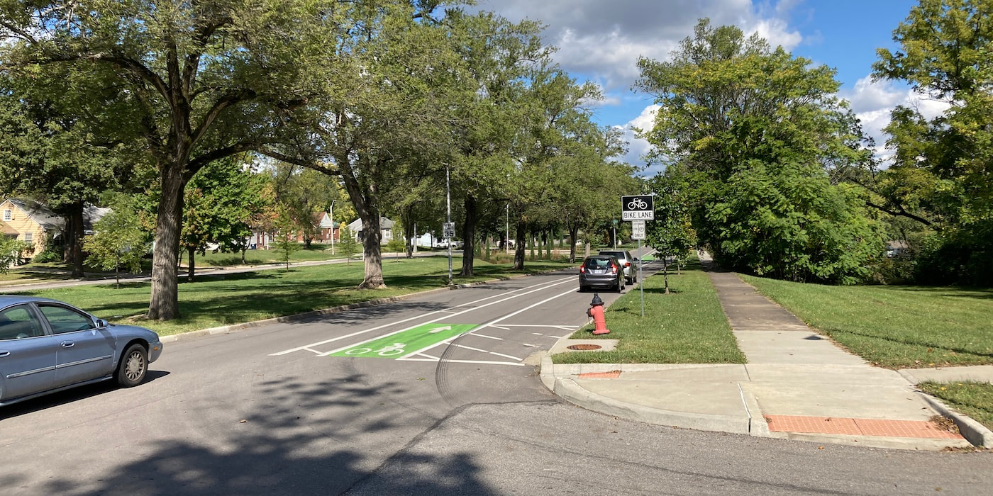 A car drives down a city street alongside a newly painted bike lane.