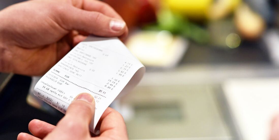 Image of hands holding a grocery receipt, with product in the background.