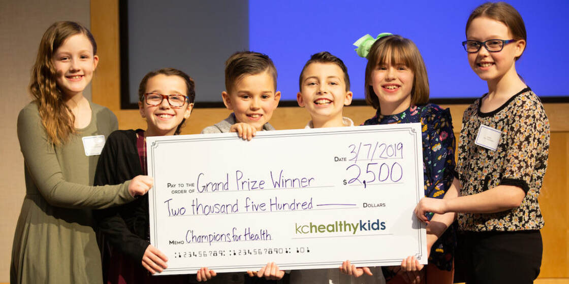 A group of elementary students pose with a check for $2,500
