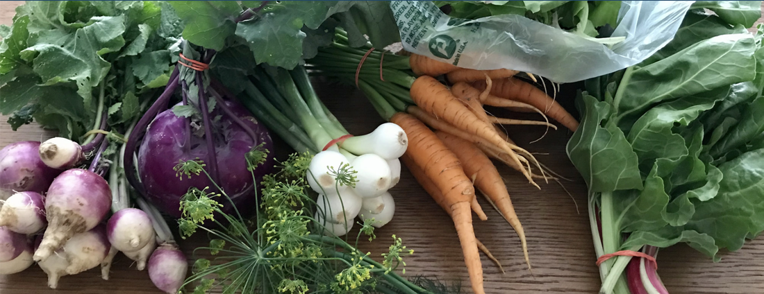 Image of turnips, kohlrabi, dill, onions, carrots and greens on a market table.